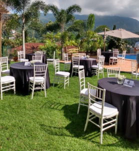 Evento corporativo com mesas redondas e cadeiras tiffanys brancas.